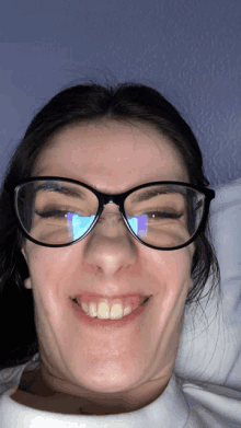 a woman wearing glasses makes a funny face with her eyes closed