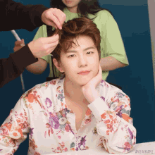 a man in a floral shirt is getting his hair done