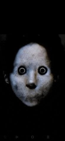 a close up of a scary doll 's face with big black eyes in the dark .