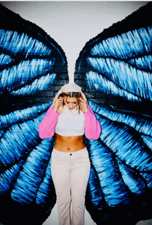 a woman is standing in front of a mural of a butterfly wing