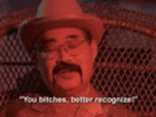 a man with a mustache and glasses is wearing a cowboy hat and talking .