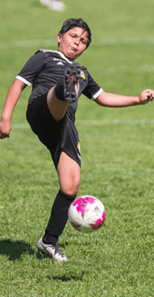 a young boy kicking a soccer ball with the number 7 on his shirt