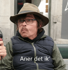 a man wearing a hat and glasses with the words aner det ik written below him