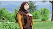 a woman in a hijab is standing in a park .