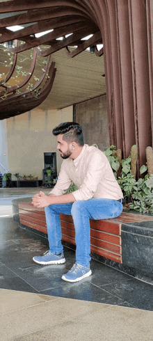 a man is sitting on a wooden bench with his legs crossed