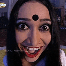 a woman with a bindi on her forehead is smiling and making a funny face