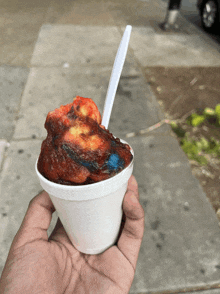 a person is holding a cup of red and blue ice cream