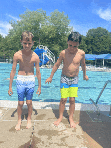 two young boys standing on the edge of a pool