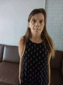 a woman making a funny face while standing in front of a brown couch