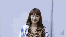 a woman wearing a leopard print shirt and a blue and white blanket with bnk48 written on it