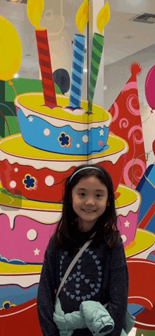 a little girl is standing in front of a birthday cake