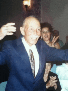 an elderly man in a suit and tie is dancing