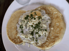 a white plate topped with pancakes and a fried egg on top