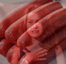 a woman is surrounded by a bunch of sausages and looking at them .