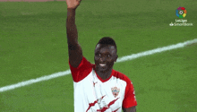 a soccer player is waving his hand in the air while standing on a field .