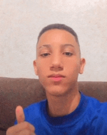 a young man is sitting on a couch giving a thumbs up .