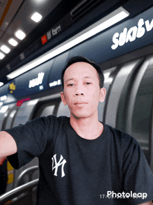 a man wearing a ny yankees t-shirt stands in front of a sign that says subway