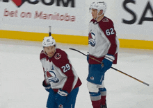 a hockey player with the number 29 on his jersey stands next to another player with the number 62 on his jersey