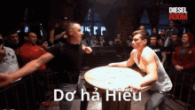 two men are wrestling in front of a crowd and the words do ha hieu are visible