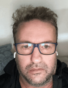 a man with a beard wearing glasses and earbuds