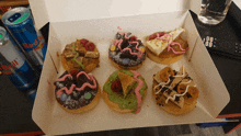 a box of donuts sits on a table next to two cans of red bull