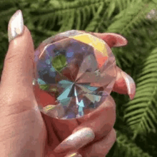 a woman 's hand is holding a large diamond shaped crystal .