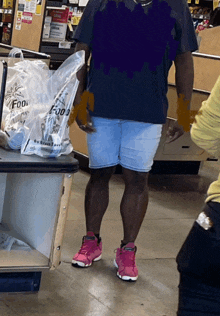 a man in a black shirt is standing in front of a bag that says ' foods ' on it