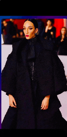 a woman in a black coat is standing on a runway