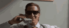 a man wearing sunglasses is talking on a cellphone