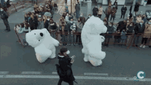 a man taking a picture of two polar bears in front of a crowd with the letter c in the corner