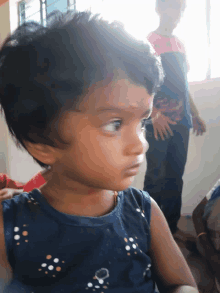 a little girl wearing a blue shirt with polka dots on it