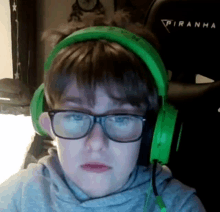 a young boy wearing glasses and green headphones is looking at the camera .