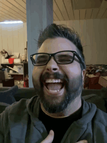 a man with glasses and a beard laughs with his mouth open