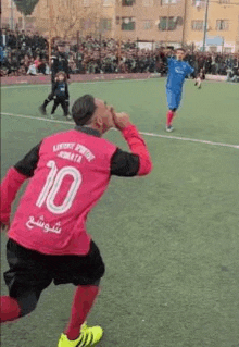 a man in a pink shirt with the number 10 on it is playing soccer .