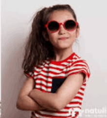 a little girl wearing sunglasses and a red and white striped shirt .