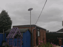 a satellite dish is sitting on top of a pole in a backyard