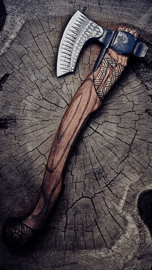 a large axe with a wooden handle is sitting on a tree stump .