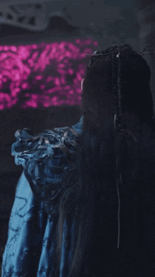 a man with long hair is wearing a blue cloak