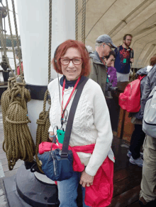 a woman wearing glasses and a lanyard that says ' north face ' on it smiles for the camera