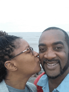 a woman kisses a man on the cheek while they are posing for a picture