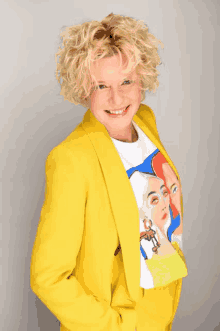 a woman wearing a yellow suit and a t-shirt with a painting of three women on it