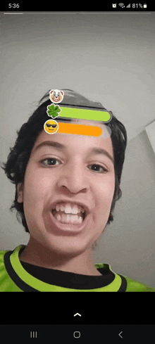 a young man is making a funny face with emojis on his face .