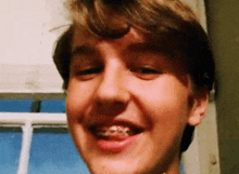 a young boy with braces on his teeth is smiling at the camera .