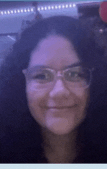 a woman with curly hair wearing glasses and smiling