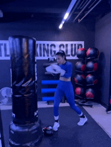 a woman is hitting a punching bag in a gym that says king club on the wall