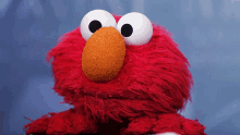 elmo from sesame street is sitting on a table and looking at the camera