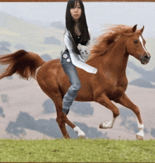 a woman is riding on the back of a brown horse in a field