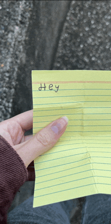 a person is holding a piece of paper with the word hey written on it