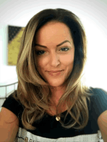 a woman with long blonde hair and a black shirt smiles for the camera