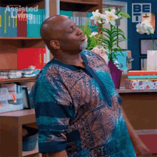 a man in a blue shirt is standing in front of a bookshelf with assisted living written on it .